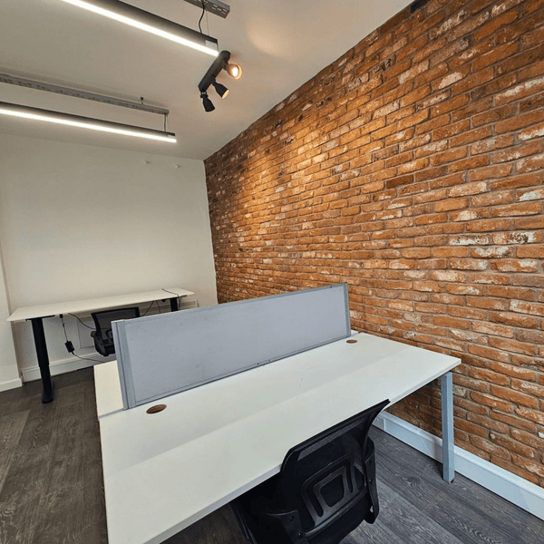 Unit 311 at 109 Portland St, Manchester: natural light-filled office with seven desks, modern design, and shared common areas.