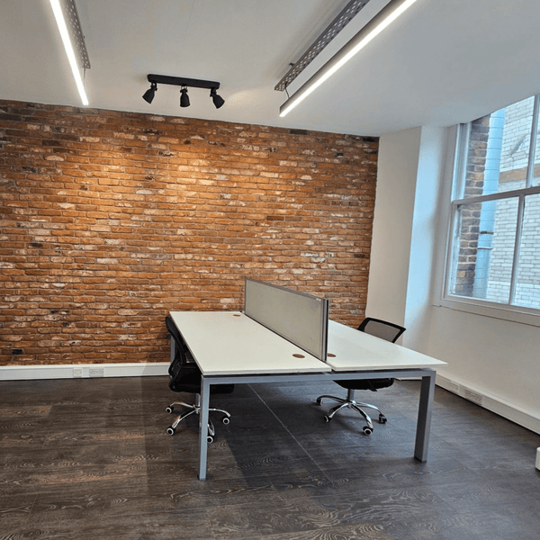 Bright office space in Manchester with seven desks, high ceilings, and a comfortable common area, featuring essential amenities.