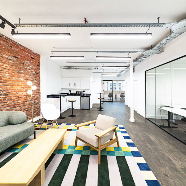 A well-lit, tidy kitchen common area in a serviced office, featuring modern appliances, furniture and ample space for gatherings.