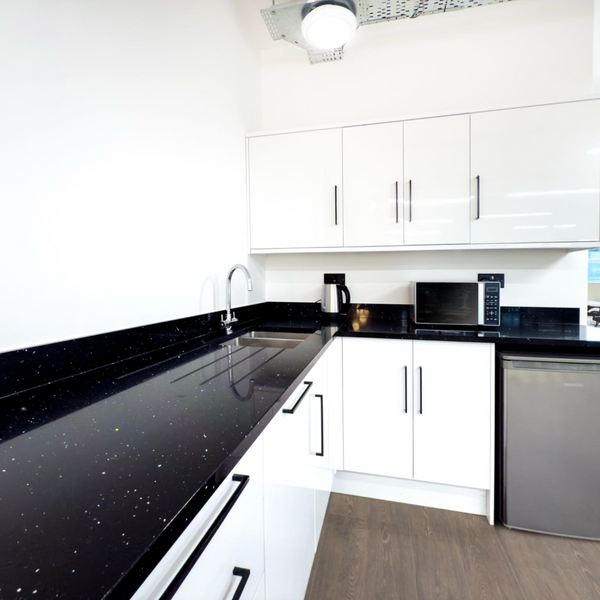 A spacious, clean kitchen common area in a serviced office, with natural light and all necessary equipment for meal preparation.