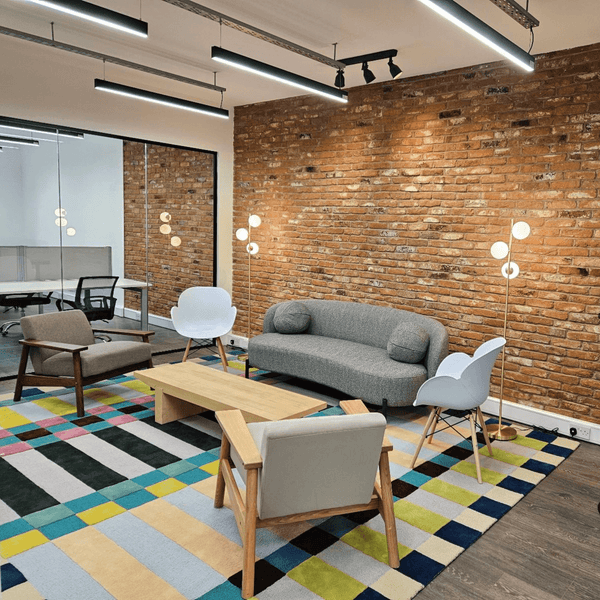 Living room-style break room in Portland Plaza, Manchester, with a couch, chair, and table for serviced office use.