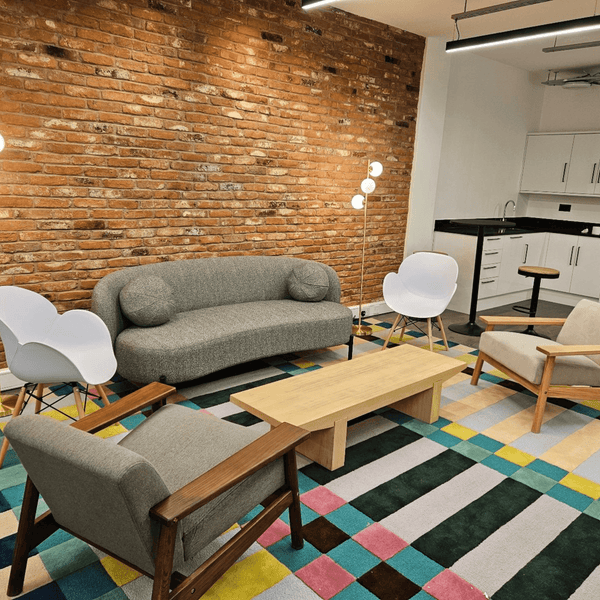 A break room of serviced offices in Portland Plaza, Manchester, featuring a couch, chair, table, and fully equipped kitchen arranged for relaxation and collaboration.