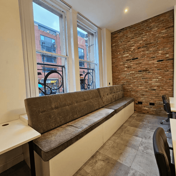For Rent: Unit G1, a bright serviced office with 5 desks, high ceilings, and modern amenities and comfortable couch on Portland Street, Manchester.
