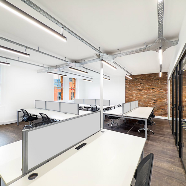 Spacious office for rent with 16 ergonomic chairs, plug-and-play desks, high ceilings, and ample natural light from large windows.