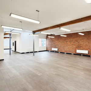Whole office floor for rent in Manchester. Modern interior with wooden flooring, exposed beams, and a brick wall.