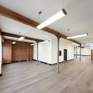 Whole office floor for rent in Portland St. Manchester. Modern interior with exposed wooden beams, white walls, and gray flooring.
