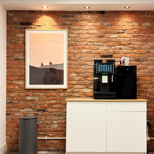 Method Spaces - Portland Plaza lobby with coffee machine on a white cabinet against a brick wall with a framed picture.