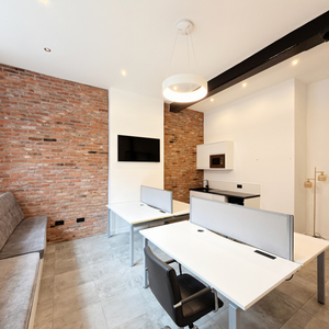 Modern office space for rent with a brick wall, desk, and chair. Located at Portland St. Manchester.